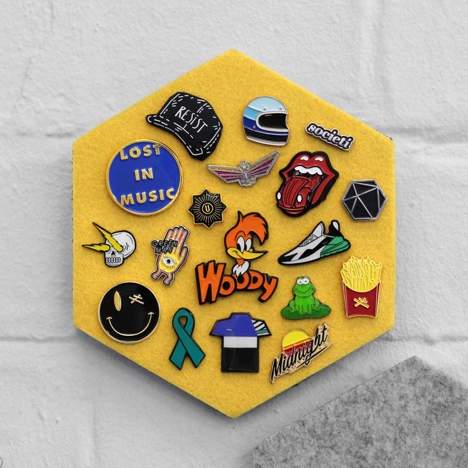 Pin badges displayed on a yellow hexagon felt board